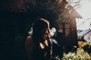 Young woman smoking cannabis outside of her house